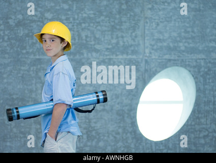 Boy holding document tube under arm and wearing hard hat Stock Photo
