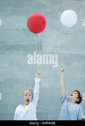 Two children holding balloons, shouting Stock Photo