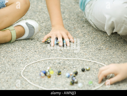 Children playing marbles on asphalt Stock Photo