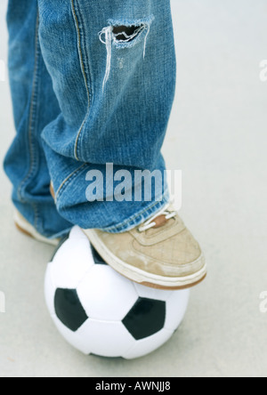 Boy resting foot on soccer ball, close-up Stock Photo
