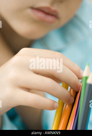 Child touching colored pencils Stock Photo