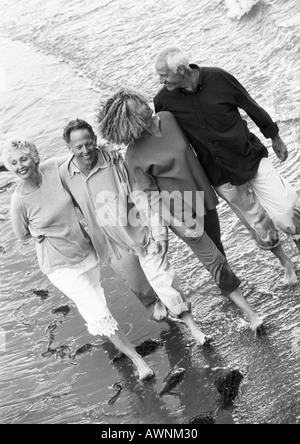 Two mature couples walking down the beach together, view from above, B&W Stock Photo