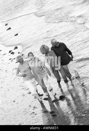 Two mature couples walking down the beach together, view from above, B&W Stock Photo