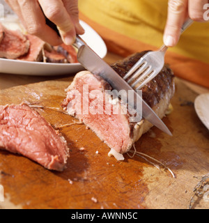 Close-up of hands cutting roast beef Stock Photo