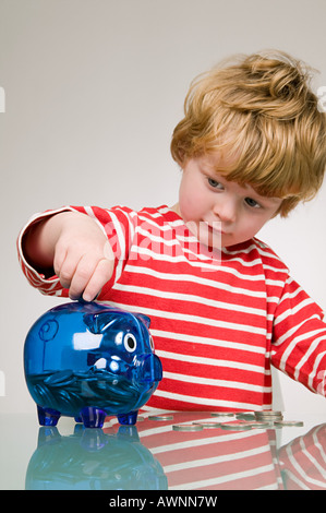 Boy putting money in piggy bank Stock Photo