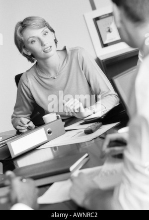 Businesswoman listening to colleague, B&W Stock Photo