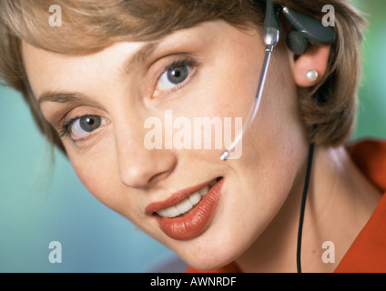 Woman wearing headset, looking at camera, close-up, portrait Stock Photo