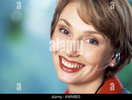 Woman wearing headset, smiling at camera, close-up, portrait Stock Photo