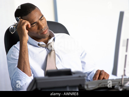 Businessman sitting at desk with eyes closed Stock Photo