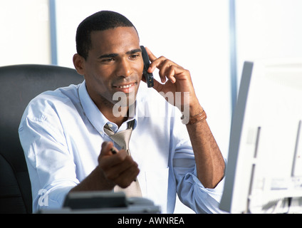 Businessman sitting at desk, using telephone Stock Photo
