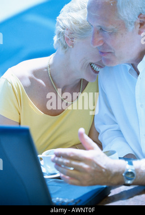 Mature woman and man sitting outdoors with laptop computer Stock Photo