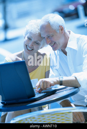Mature woman and man sitting at a cafe terrasse with laptop computer Stock Photo