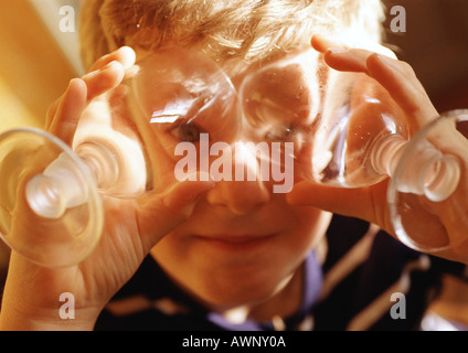 Child holding wine glasses in front of eyes, portrait Stock Photo