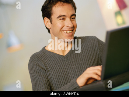 Man using laptop computer, smiling, close-up Stock Photo
