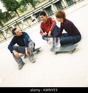 Young people sitting outdoors with skateboards Stock Photo