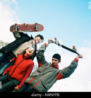 Young woman between two young men holding skateboards, portrait Stock Photo