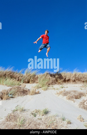 Young Man leaping from a Sand Dune Braunton Burrows Devon UK Stock Photo