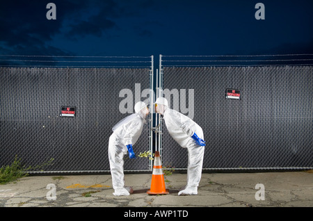 People in biohazard suits kissing over orange safety cone Stock Photo