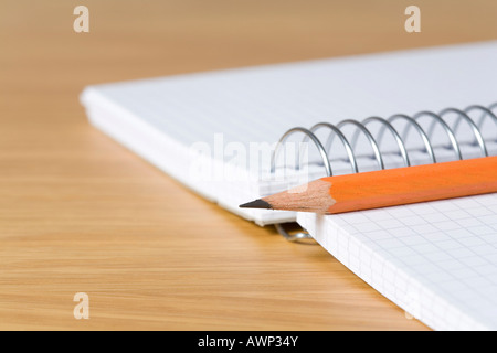 Pencil placed on top of a spiral notebook Stock Photo