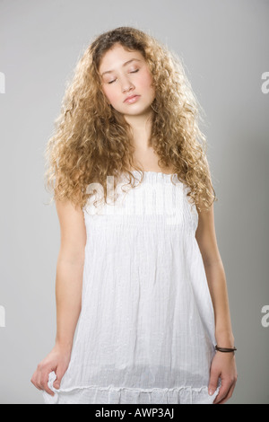 Young woman with long, curly hair wearing a white dress Stock Photo