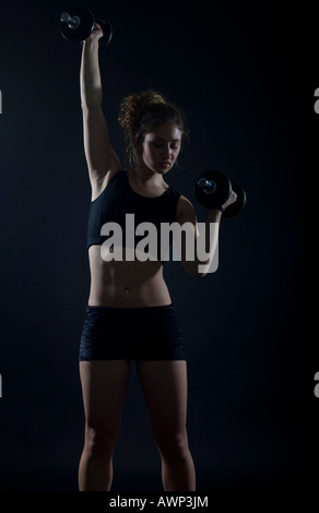 Young woman working out with dumbbells Stock Photo