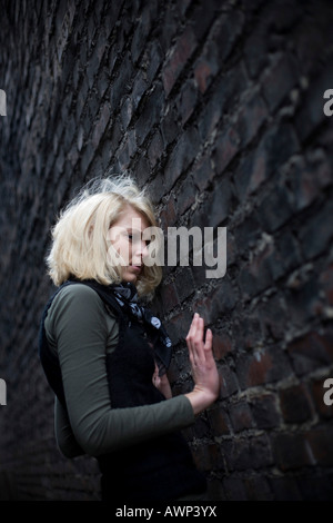 Blonde woman standing in front of a stone wall