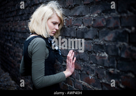 Blonde woman standing in front of a stone wall
