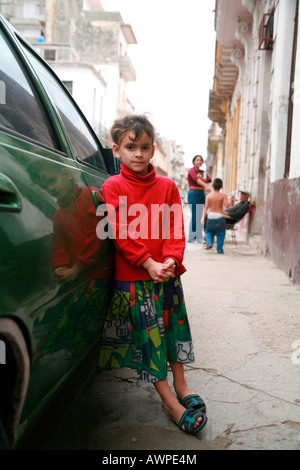 Girl leaning against a car parked on a street in Havana, Cuba, Caribbean Stock Photo