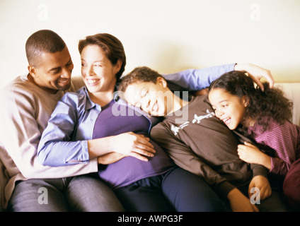 Couple and children sitting on sofa Stock Photo