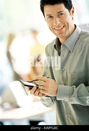 Businessman using pocket computer, smiling, portrait Stock Photo
