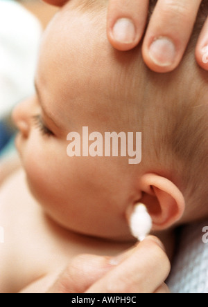 Baby having ear cleaned with cotton swab, close-up Stock Photo