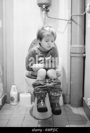 Little girl sitting on toilet, b&w Stock Photo