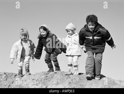 Three girls and boy holding hands, preparing to jump, b&w Stock Photo