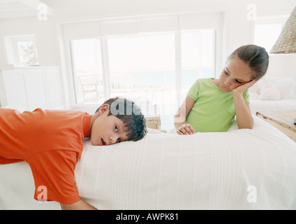 Two children resting on bed, one looking at camera Stock Photo