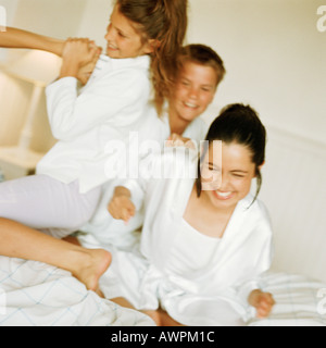 Young people playfighting on bed, smiling Stock Photo