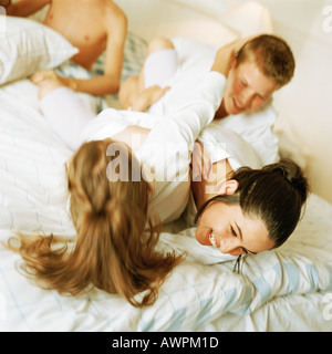 Young people play fighting on bed, smiling Stock Photo