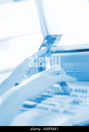 Hands holding credit card and typing on computer keyboard, close-up Stock Photo