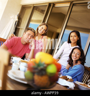 Teenage girls with parents at table, smiling Stock Photo