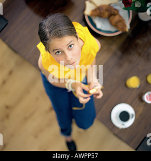 Child sitting on edge of table, looking at camera, high angle view Stock Photo