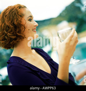 Woman holding glass, side view, portrait Stock Photo