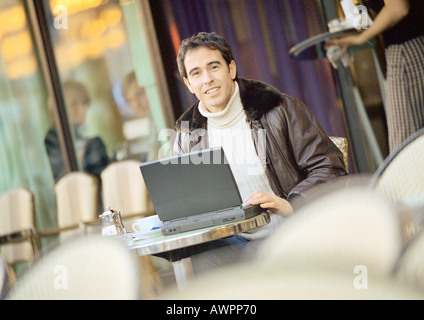 Man using laptop computer on cafe terrace Stock Photo