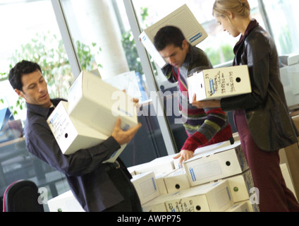 Two men and woman carrying boxes Stock Photo
