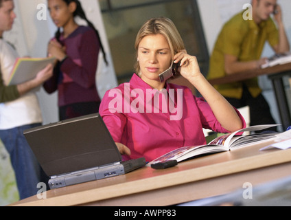 People in office, businesswoman using cell phone and laptop computer Stock Photo