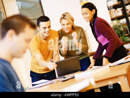 People in office, three people looking at laptop computer Stock Photo