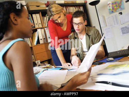 Two women and man at desk examining documents Stock Photo