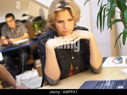 Woman with hands under chin in office Stock Photo