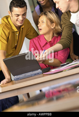 Four people grouped around laptop computer Stock Photo
