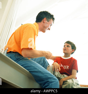 Father and son sitting, low angle view Stock Photo