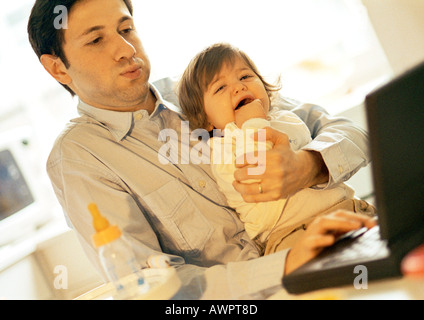Father and baby, father using laptop, baby crying Stock Photo