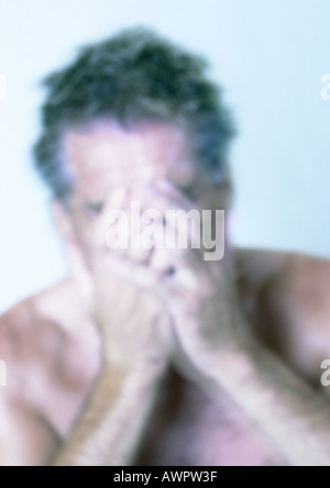 Mature man covering face with hands, close-up, portrait, blurred Stock Photo
